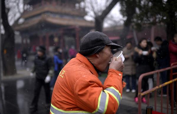 00.2017年1月5日早上，北京，雍和宫大殿前飘起了雪，环卫工人在雪中喝腊八粥。 东方IC 图.jpg