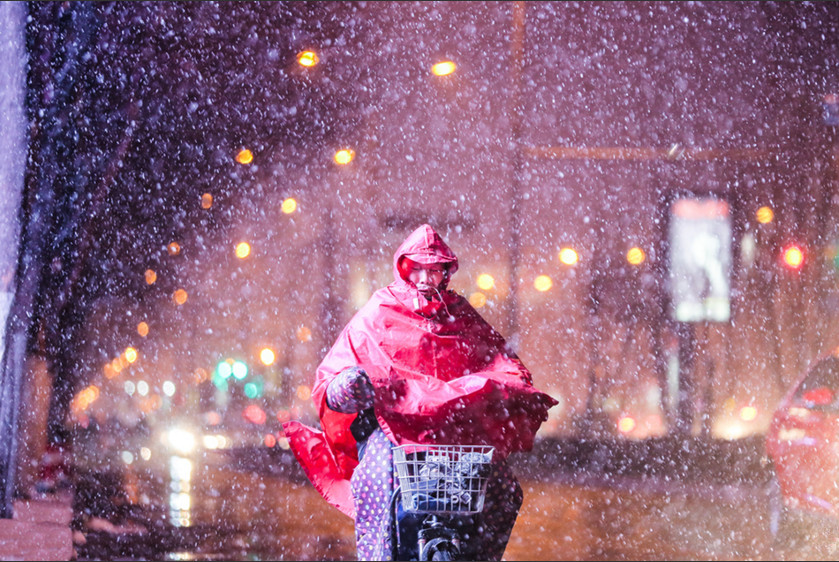 2月21日晚，山东济南迎来今春首场降雪，街头道路和建筑被大雪覆盖，市民在飞舞的大雪.jpg