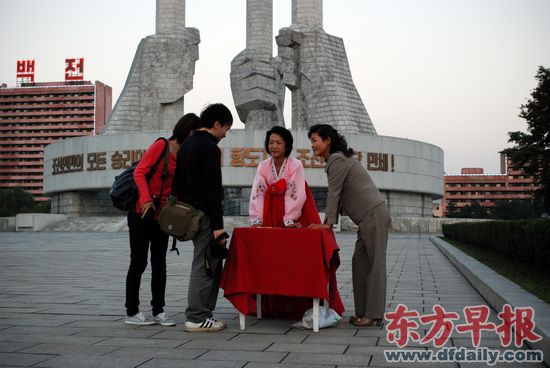 10月3日,两名朝鲜女性在朝鲜劳动党建党纪念碑前向香港游客出售旅游纪念徽章。.jpg